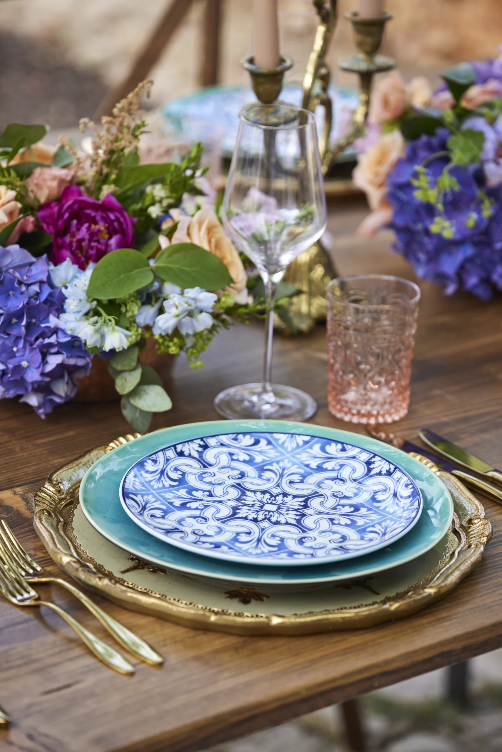 Luxury wedding table setting in Portugal featuring blue patterned tile tableware, gold accents, and colourful floral arrangements.