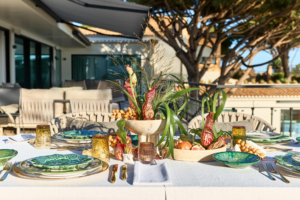 Rooftop table setting with botanical green plates, exotic blooms and gold cutlery, Algarve